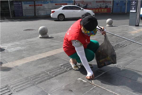 用手从砖缝里抠出烟头 只为社区文明整洁