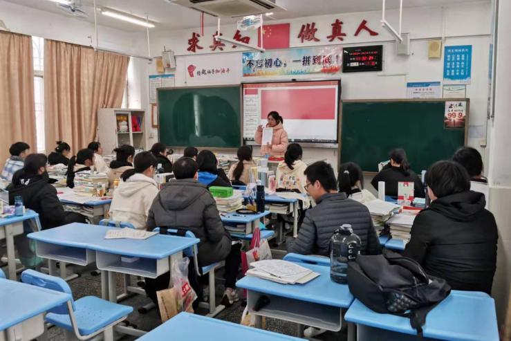 在盐港中学,顶着小雨,校长谢红越在校门口迎接返校师生.